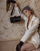 Woman carrying black lizard embossed calfskin leather shoulder box bag with large buckled belt across front, silver hardware