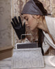 woman holding grey python embossed calfskin and suede leather handbag, with brass metal frame in silver finishing.