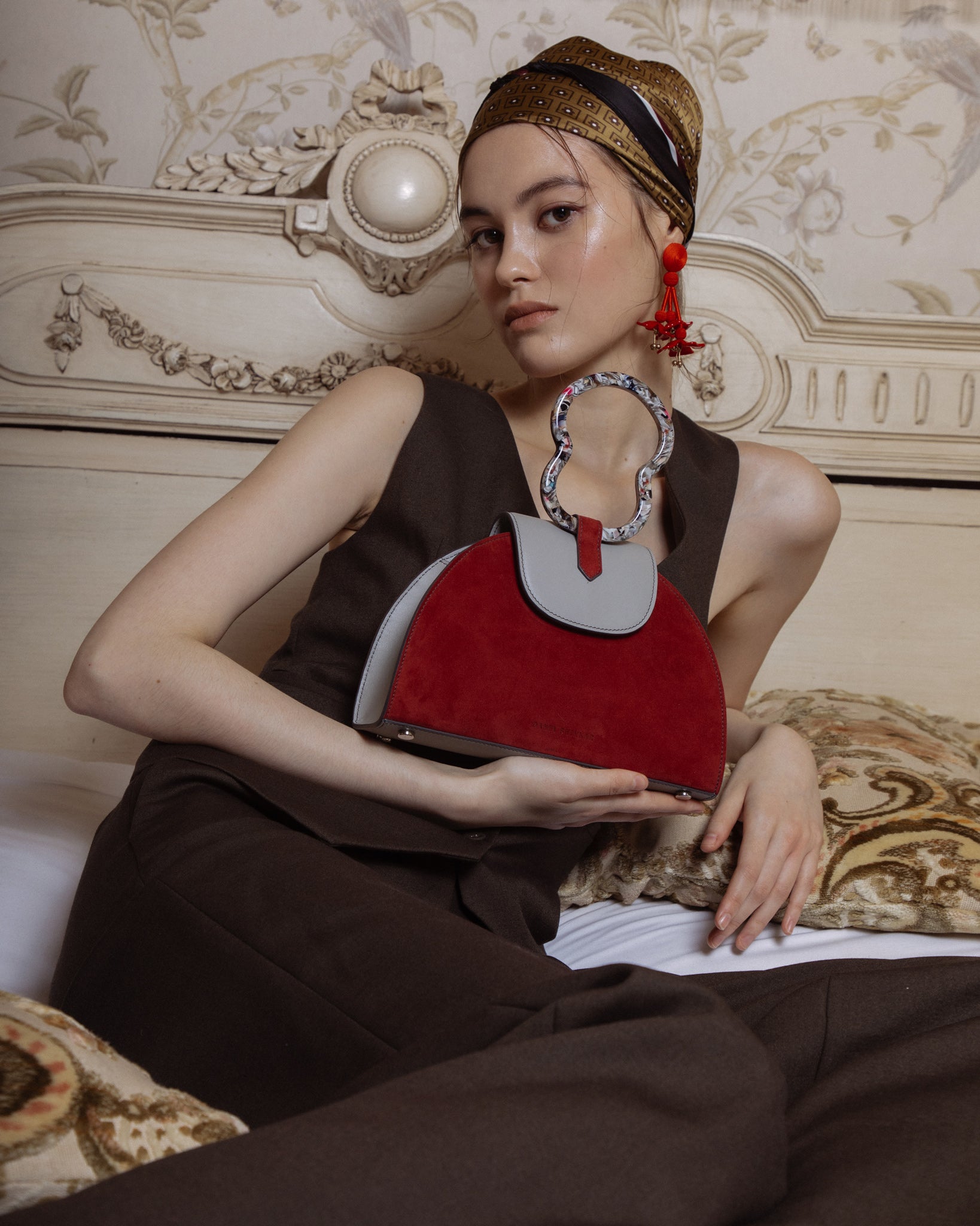 Woman carrying light grey nappa calfskin and ruby red suede leather, half moon handbag with cellulose acetate top handle.