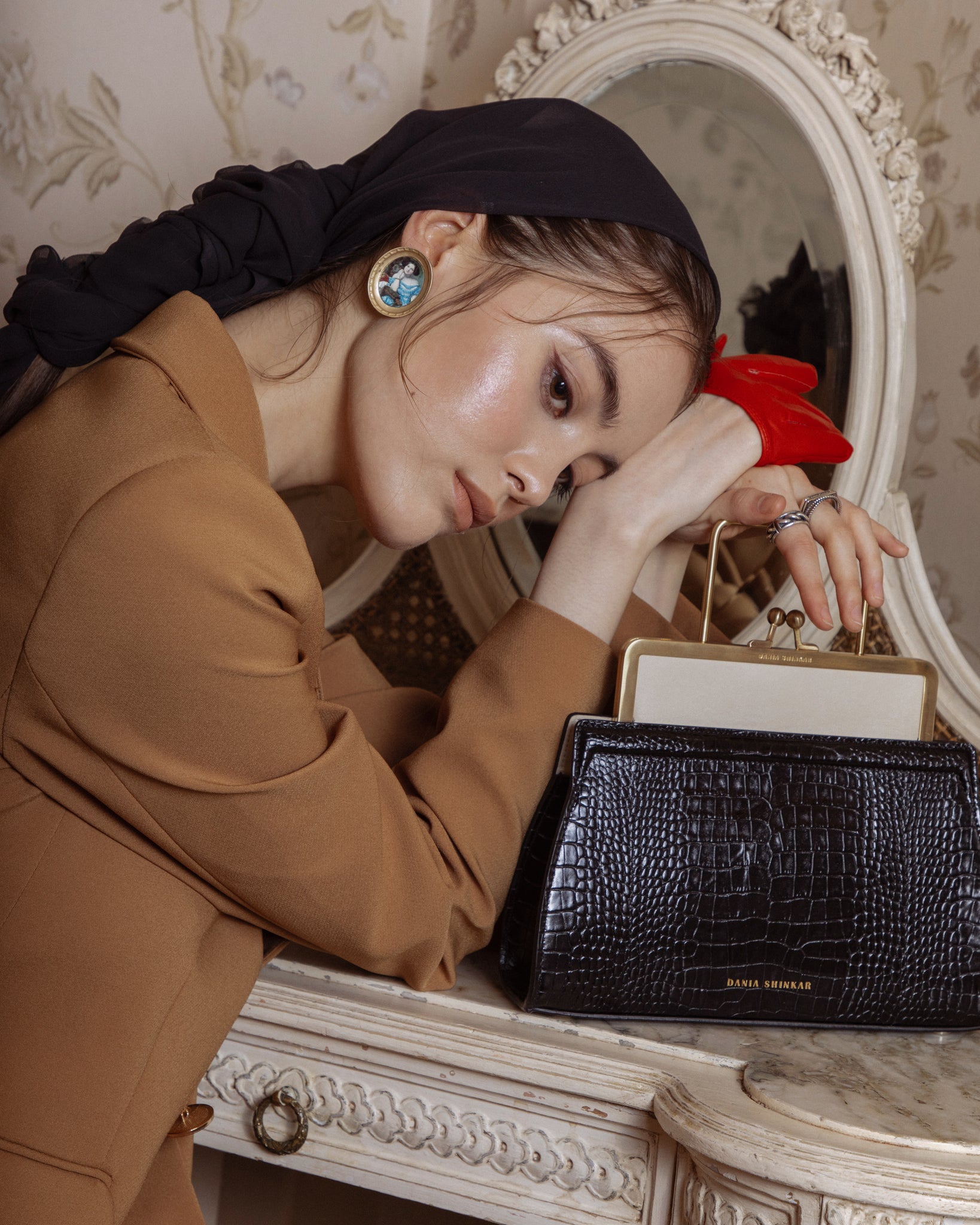 woman holding black crocodile embossed calfskin, beige nappa leather bag, with brass metal frame in light gold finishing.